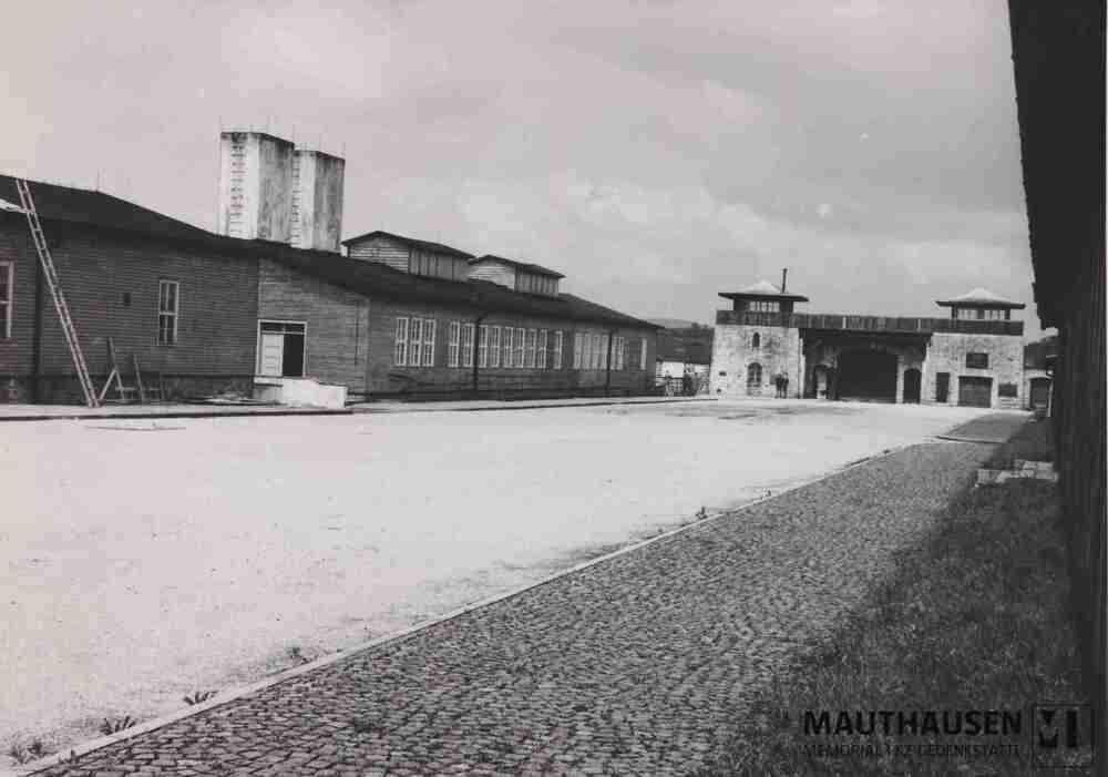 4.1.0043.jpg; 4.1.0043; KZ-Gedenkstätte Mauthausen: Ehemaliger Appellplatz, Blickrichtung Wäschereibaracke und Jourhaus (Lagertor), links die Küchenbaracke mit angelehnter Leiter, vermutlich für Dacharbeiten;