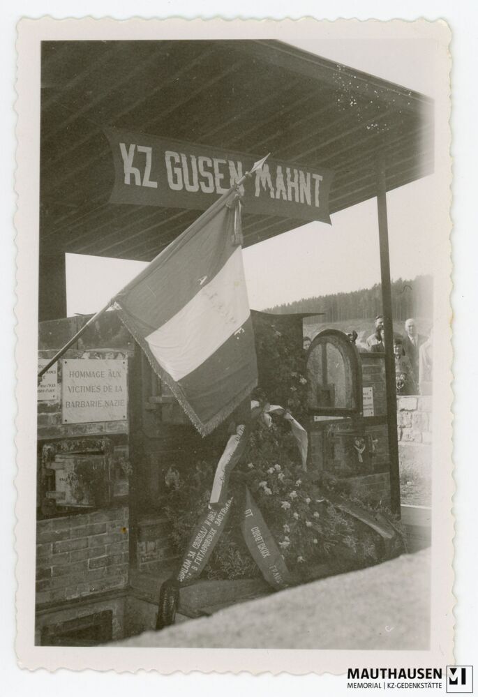 4.16.0015.jpg; 4.16.0015; Areal des ehemaligen KZs Gusen: Mit Blumenkränzen und Fahne bedeckter Krematoriumsofen;