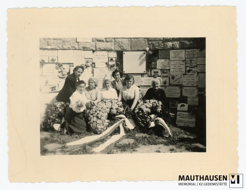 4.16.0042.jpg; 4.16.0042; KZ Gedenkstätte Mauthausen: Französische Angehörige, Witwen von im KZ Verstorbenen, haben sich vor der mit Gedenktafeln und Kränzen versehenen Gedenkwand im Inneren des Halbbogens des Französischen Denkmals gruppiert;