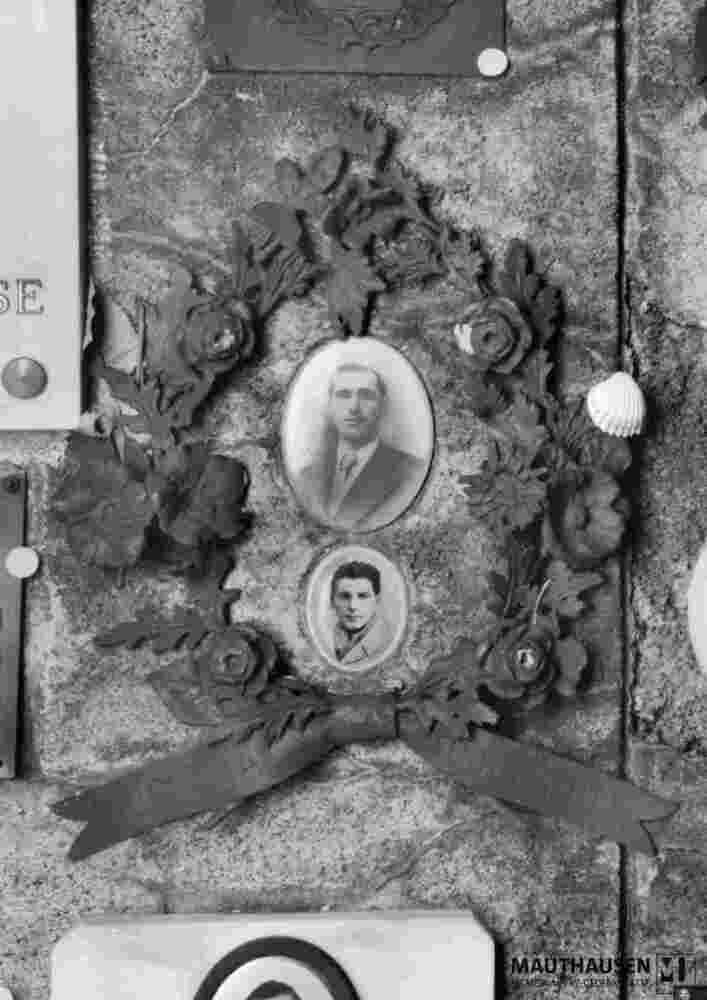 6.1.0306_01-13-058-01.jpg; 6.1.0306; Gedenkkranz der Stadt Muggiò, mit Fotomedaillons zweier unbekannter Männer; Gedenkkranz mit zwei Fotomedaillons