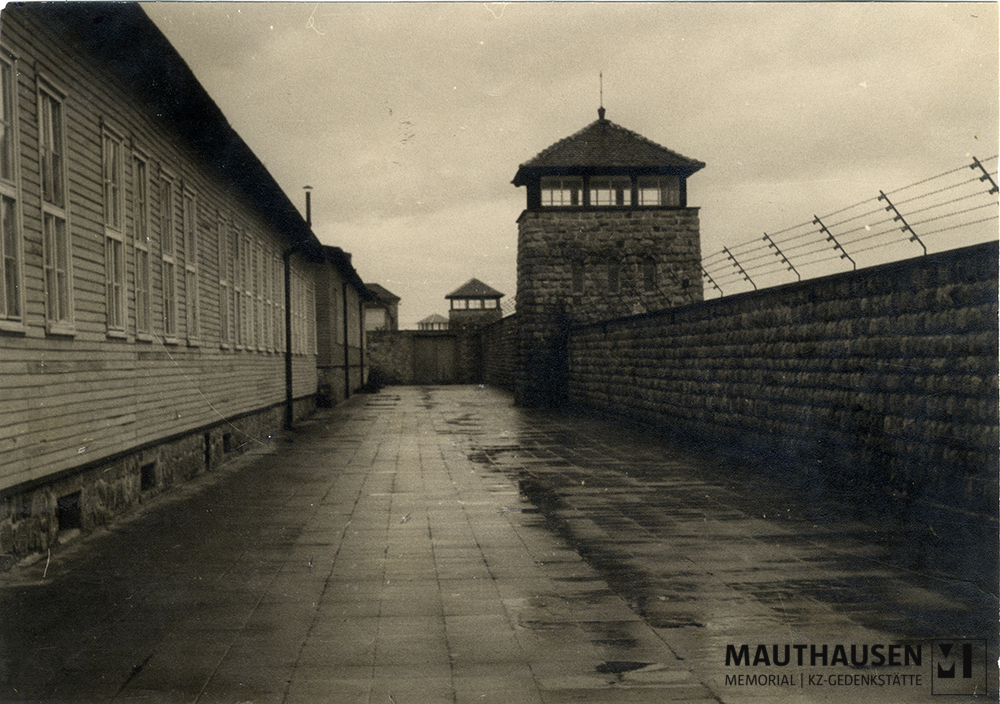 MM_4_15_001.jpg; 4.15.001; KZ Gedenkstätte Mauthausen: Ein Abschnitt der Lagermauer, ein Wachturm und in der linken Bildhälfte die ehemalige Küche- und Wäschereibaracken.; Fotografie