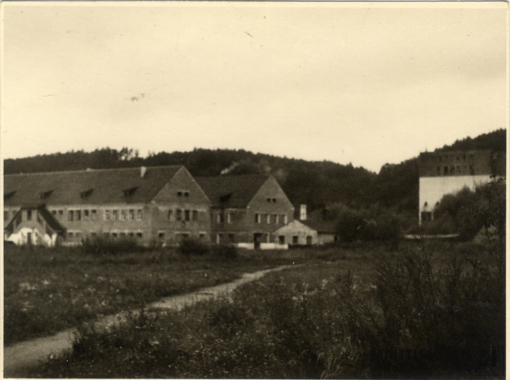 MM_4_15_006.jpg; 4.15.006; Areal des ehemaligen Konzentrationslagers Gusen: Im Hintergrund die zweigeschossigen, ehemaligen Häftlingsunterkünfte 6 und 7/8, die im Jahr 1943 fertiggestellt worden waren, sowie rechts im Hintergrund, die Überreste des Schotterbrechers. ; Fotografie