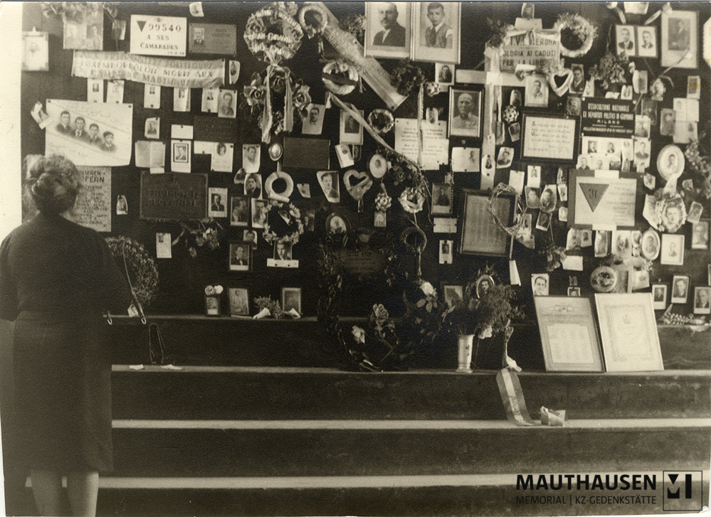 MM_4_15_014.jpg; 4.15.014; KZ Gedenkstätte Mauthausen: Miriam Novitch steht vor einer Gedenkmauer mit individuellen Erinnerungszeichen im Krematorium drei.; Fotografie