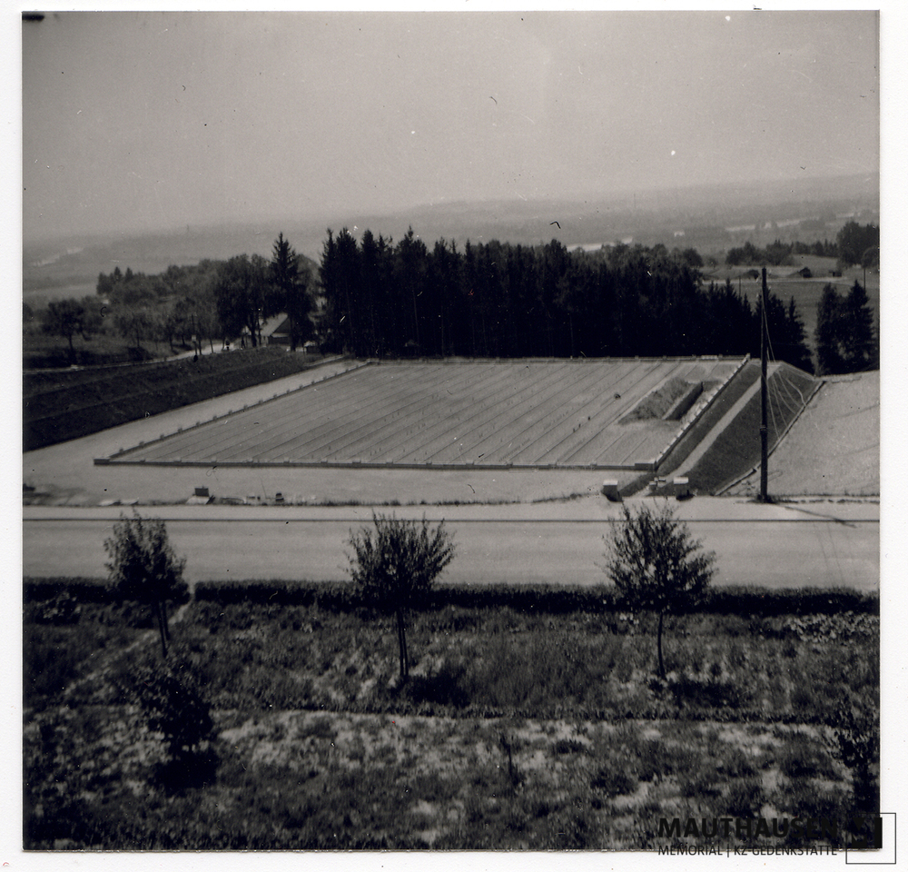MM_4_7_5_0009.jpg; 4.7.5.0009; Befreites KZ Mauthausen: Blick über die Terrassen hinunter auf das beinah zur Gänze geschlossene Massengrab auf dem Camp Cemetery Mauthausen am ehemaligen Sportplatz der SS.;
